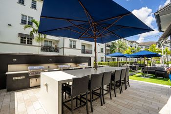 a large outdoor kitchen with a bar with chairs and umbrellas